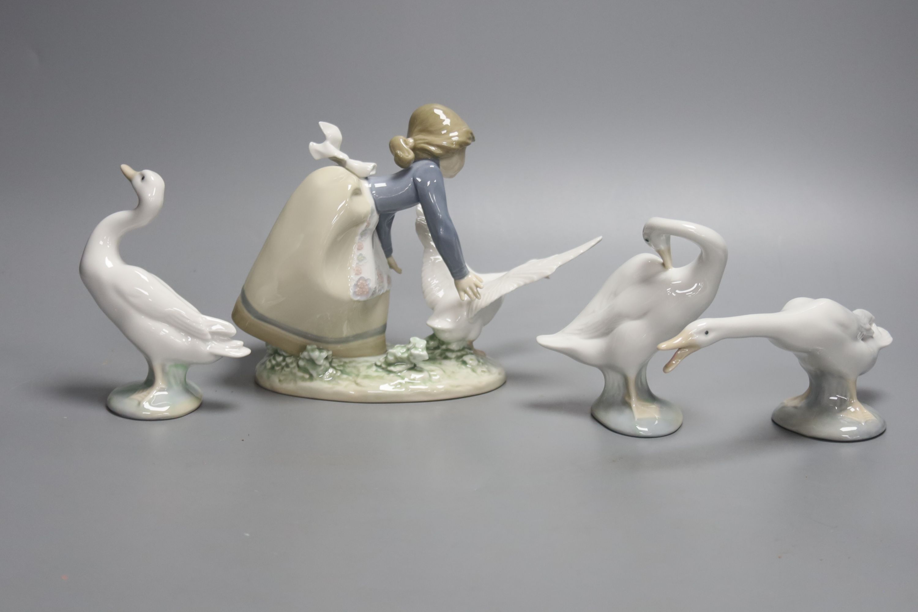 A Lladro figure of a girl with a goose and three single geese models